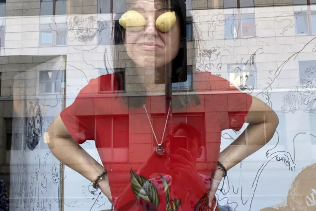 The artist with potatis on her eyes reflecting herself in a window. Photo.
