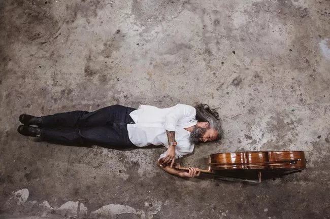 The musician lying on the ground with a cello. Photo.